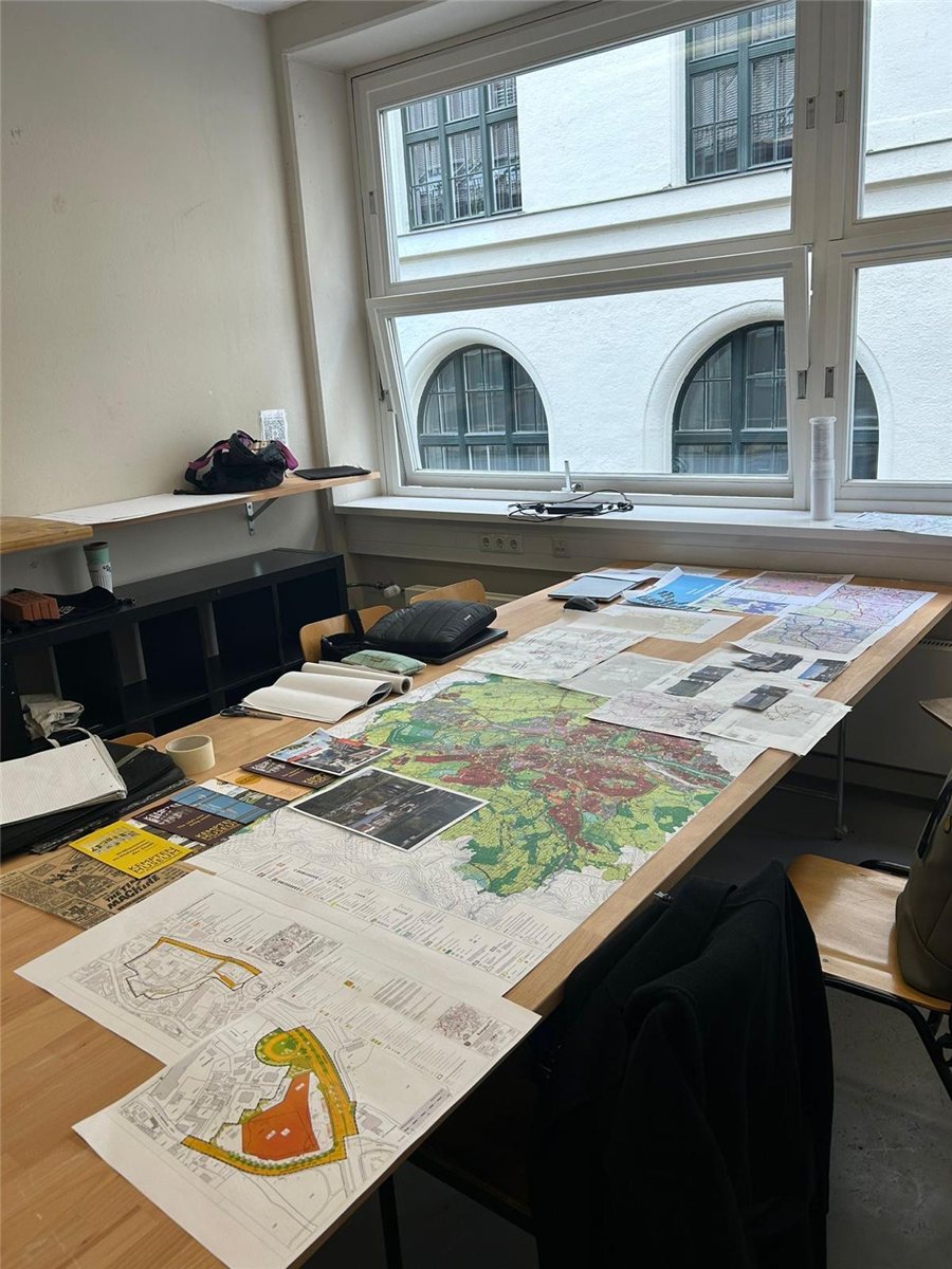 Studio table covered in site maps and drawings
