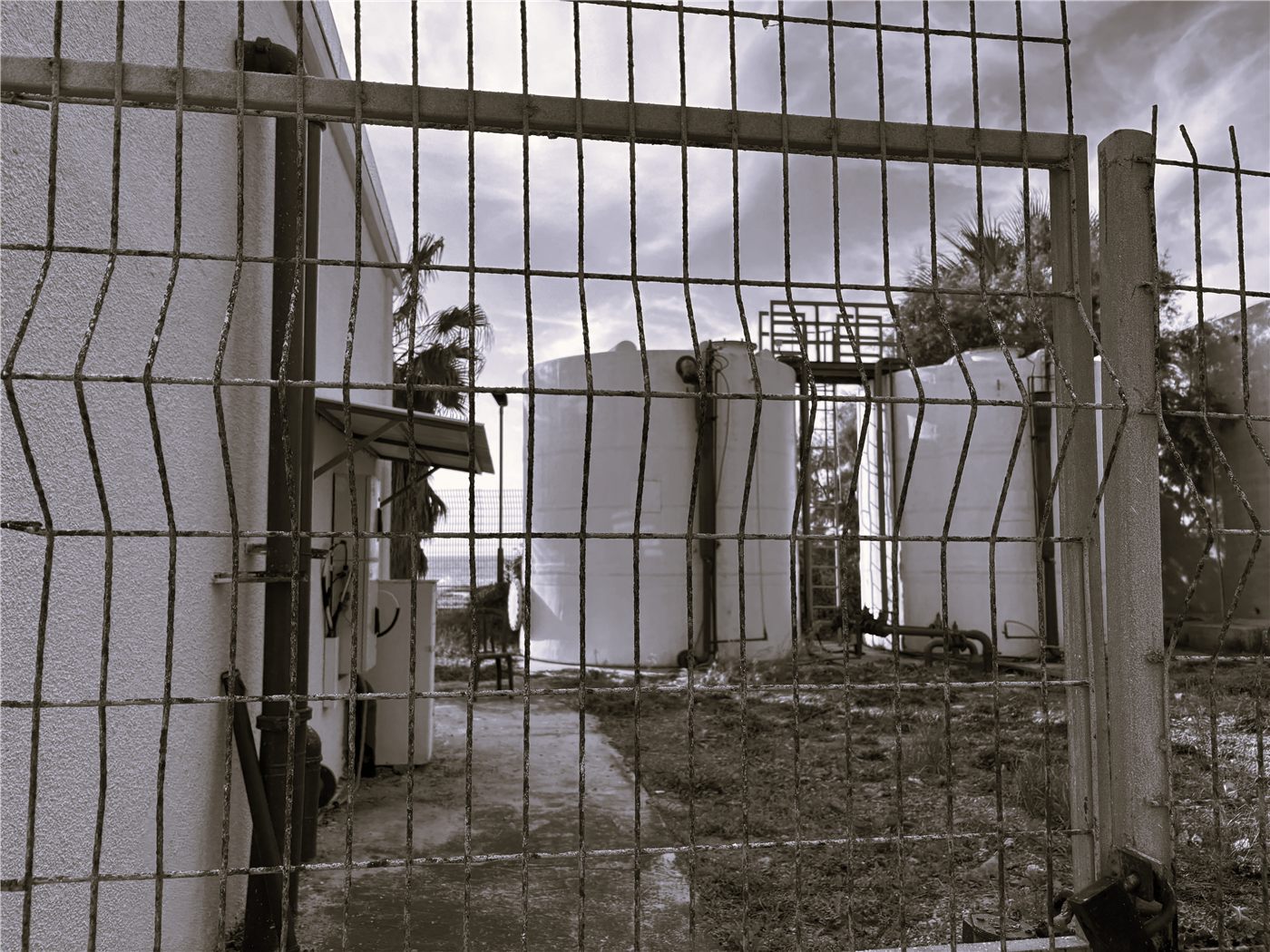 Site photo through a fence toward the water storage tanks